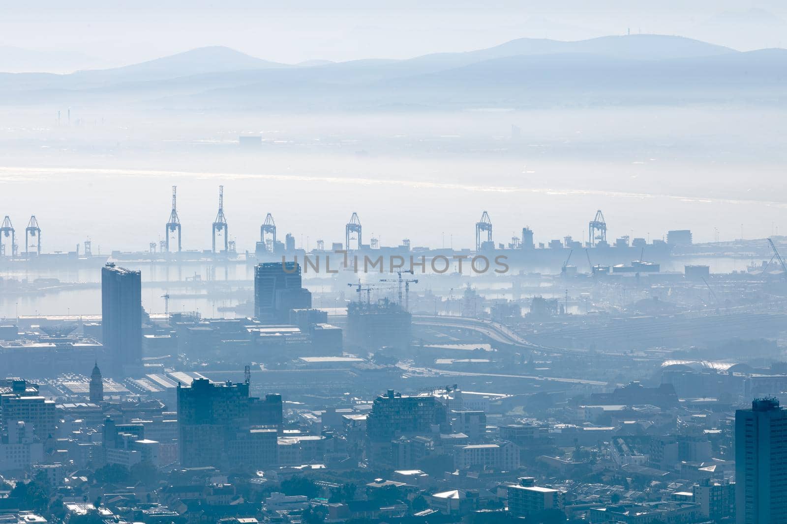 General view of cityscape with multiple modern buildings and cranes in the foggy morning. skyline and urban architecture.