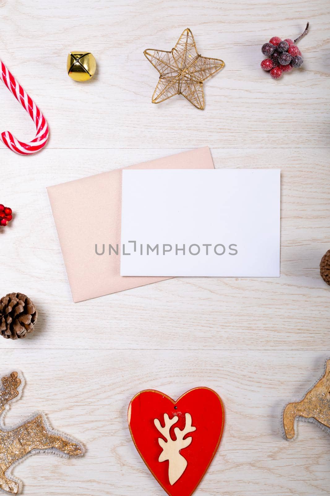 Composition of white card with copy space, envelope and christmas decorations on wooden background by Wavebreakmedia