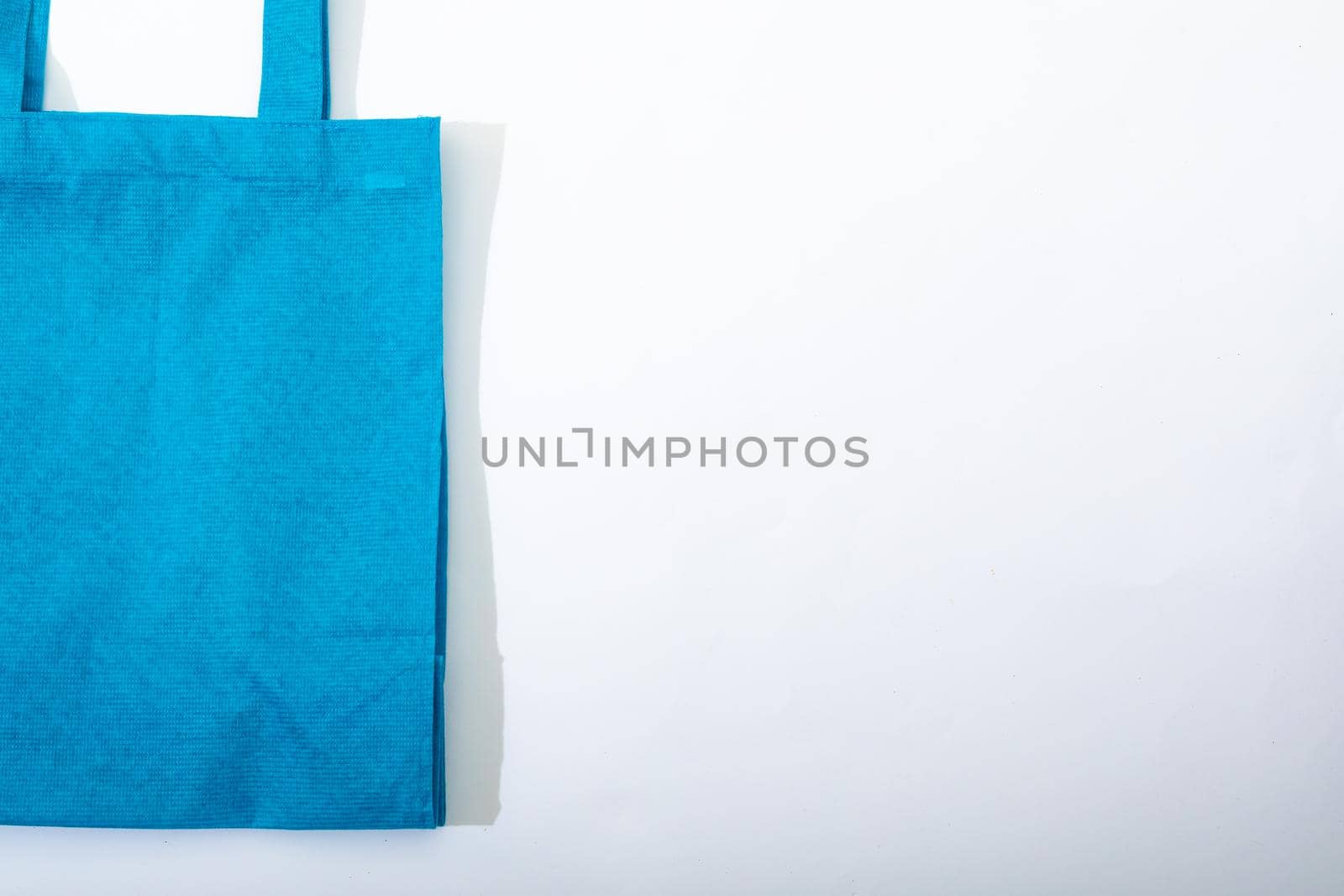 Composition of empty blue canvas shopping bag lying flat on white background. shopping and retail concept.