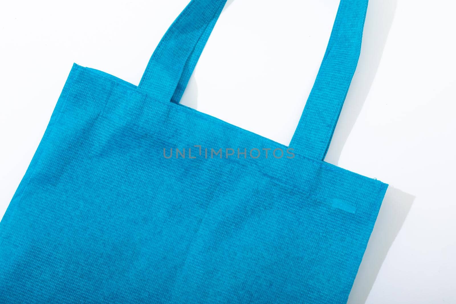 Composition of empty blue canvas shopping bag lying flat on white background. shopping and retail concept.