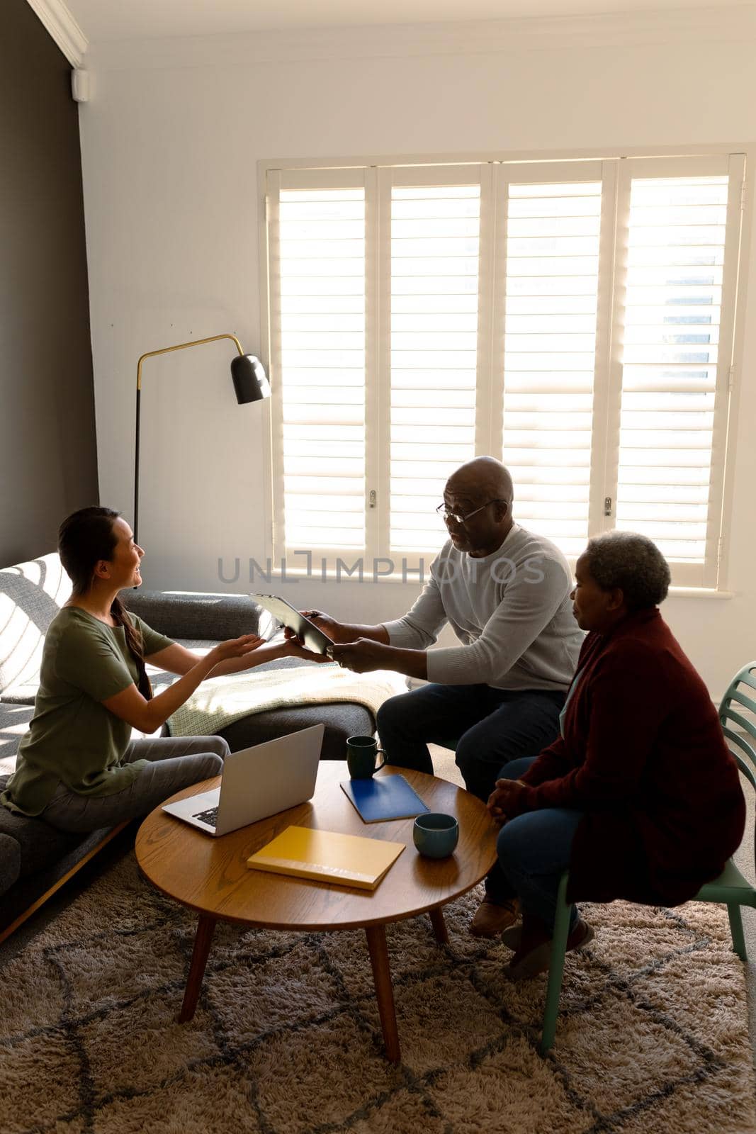 African american senior couple having meeting with asian female counselor at home. retirement lifestyle, elderly support and spending time at home.