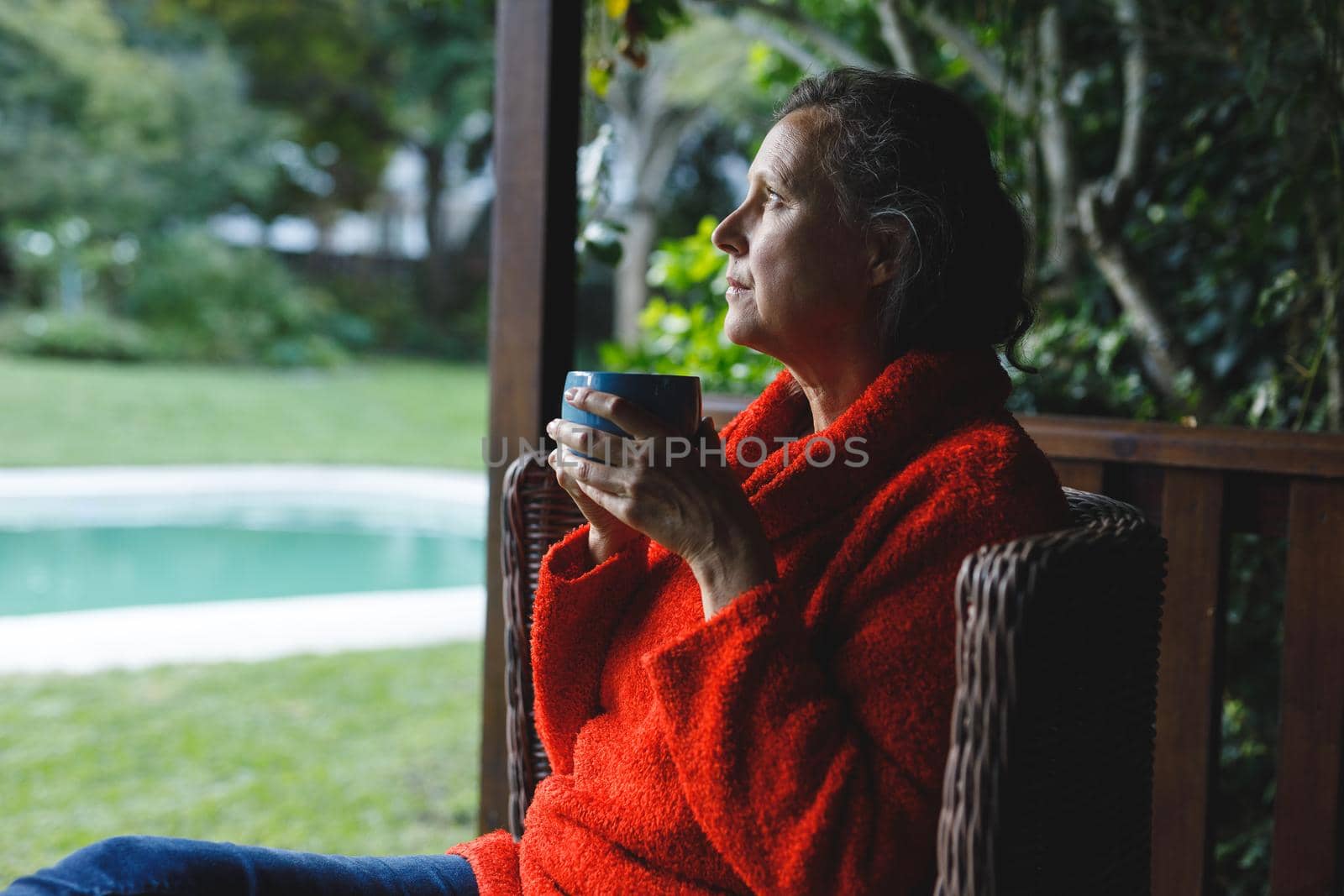 Happy senior caucasian woman sitting on chair, drinking coffee in garden. retirement lifestyle, spending time alone at home.