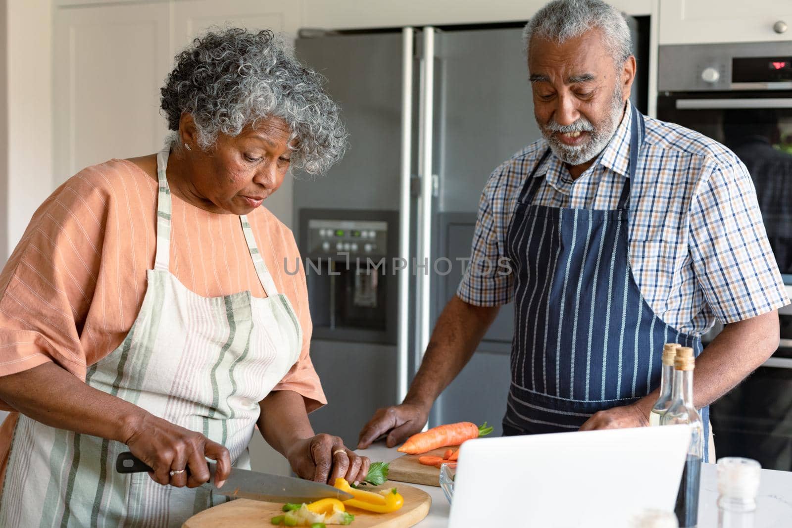 Happy arfican american senior couple cutting vegetables and preparing meal together. healthy retirement lifestyle at home.