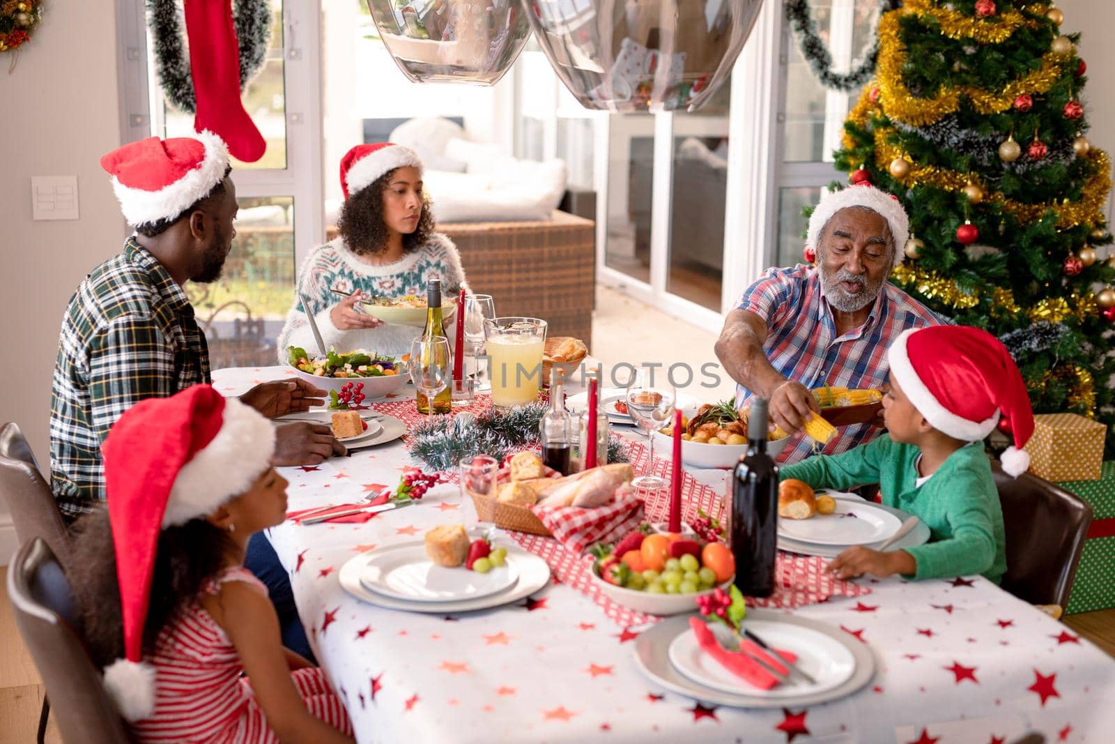 Happy multi generation family wearing santa hats, having christmas meal. family christmas time and festivity together at home.