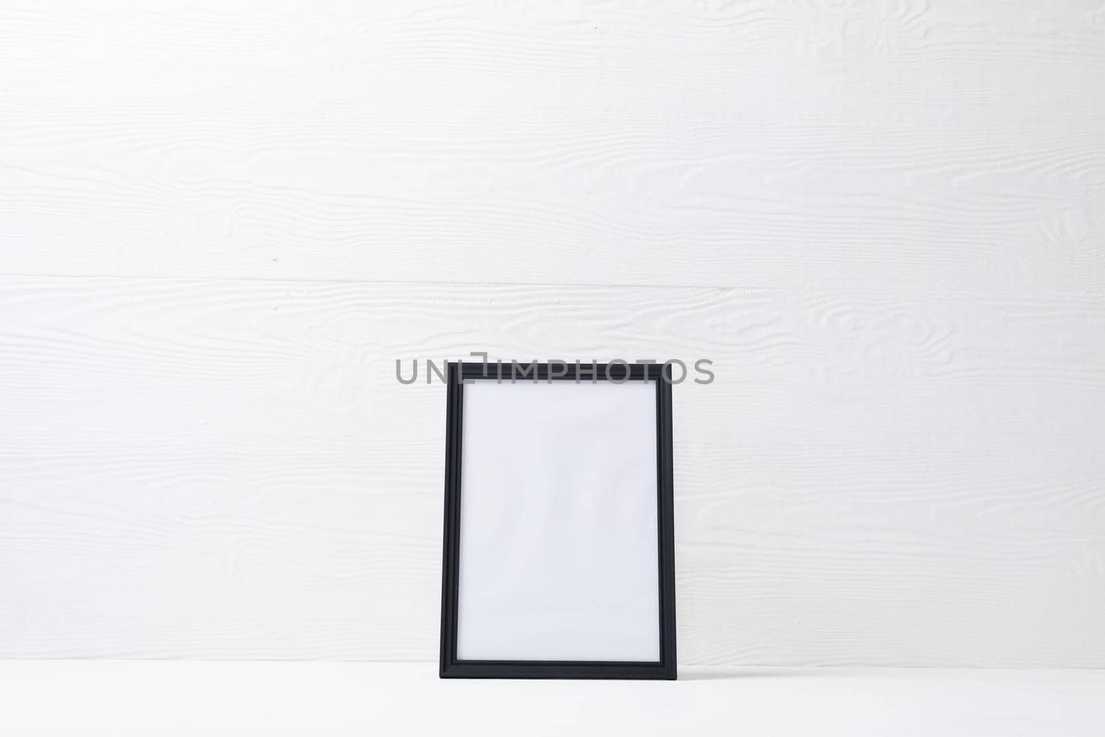 Composition of white card in black frame with copy space on white background. interior design and decor concept.