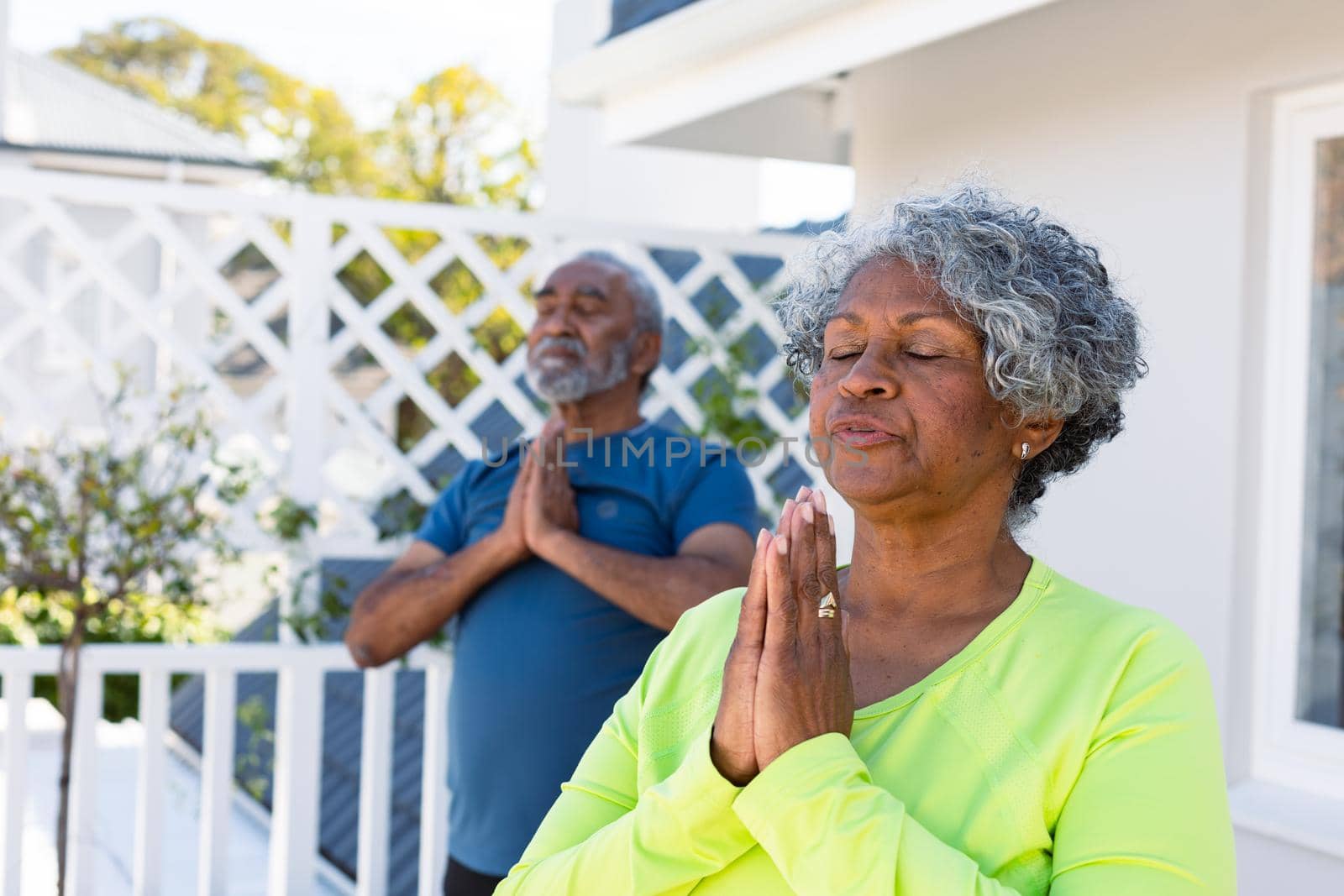 Focused african american senior couple practicing yoga in garden. active and healthy retirement lifestyle at home.