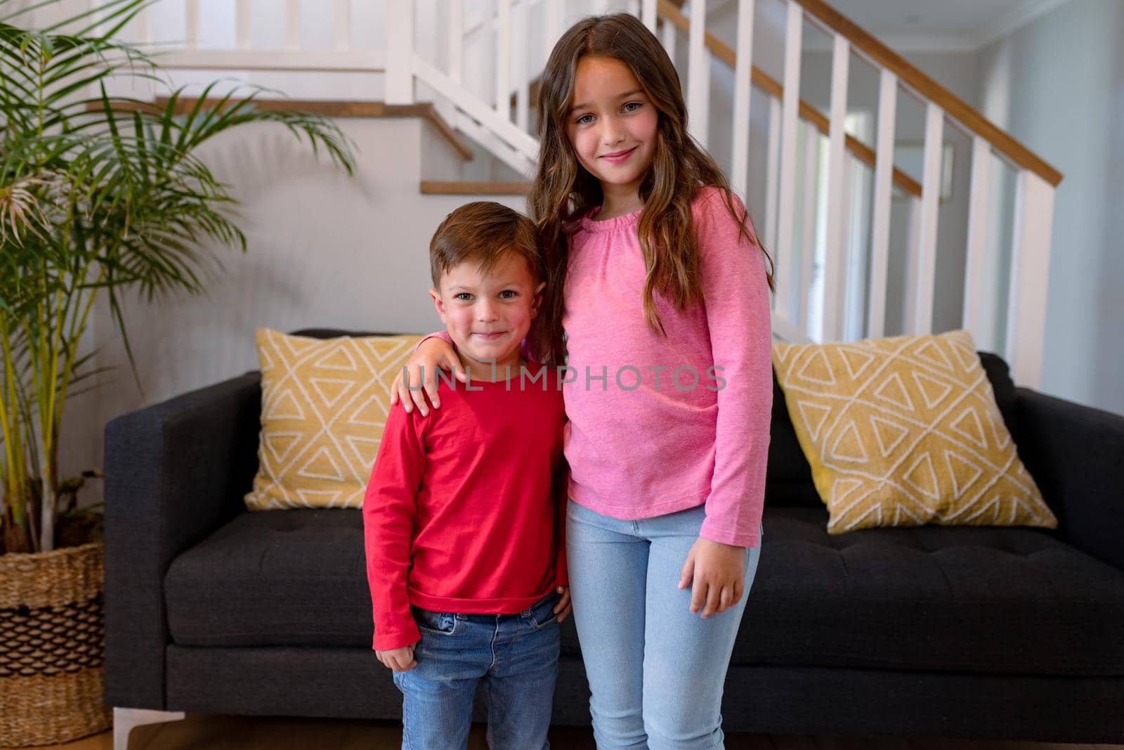 Happy caucasian siblings standing at home and looking at camera by Wavebreakmedia