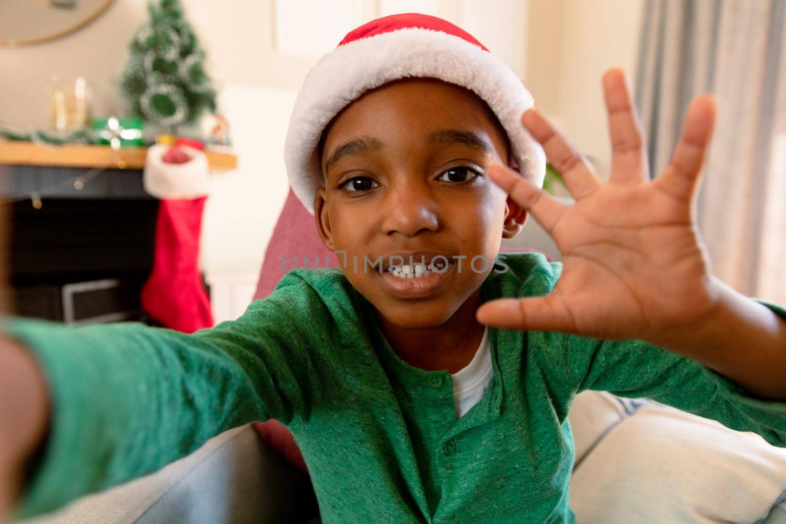 African american boy wearing santa hat making video call at christmas time. christmas, festivity and communication technology.