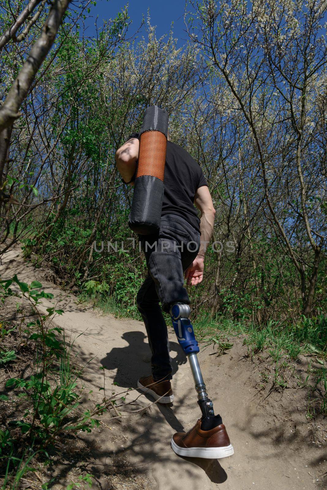 a man on a prosthetic leg travels the mountains. Dressed in black jeans and a T-shirt, he carrying mat by Ashtray25