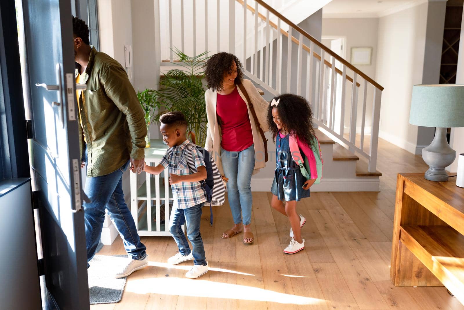 Happy african american family standing in hallway, heading to school and work by Wavebreakmedia