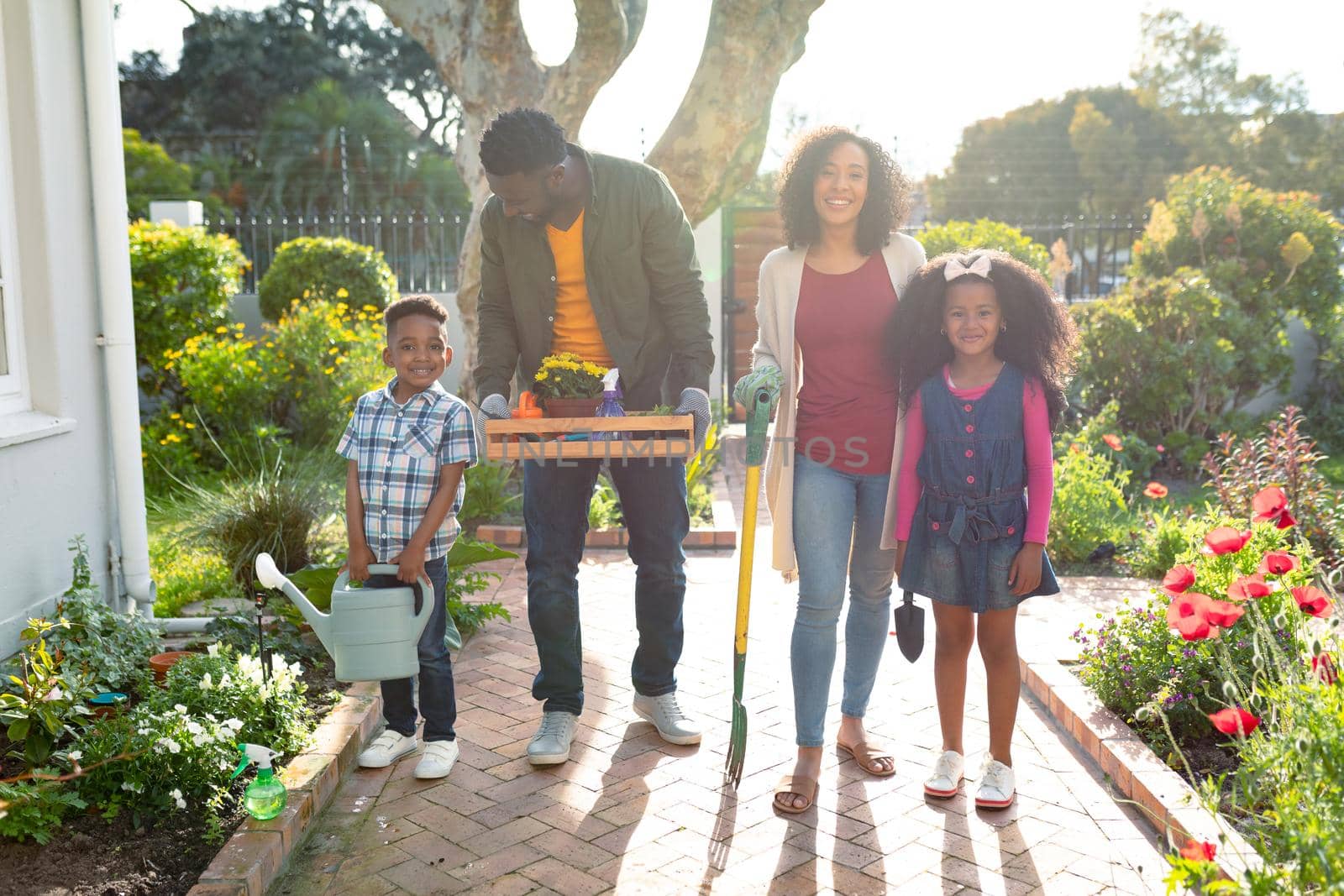 Happy african american family standing with garden tools and looking at camera by Wavebreakmedia