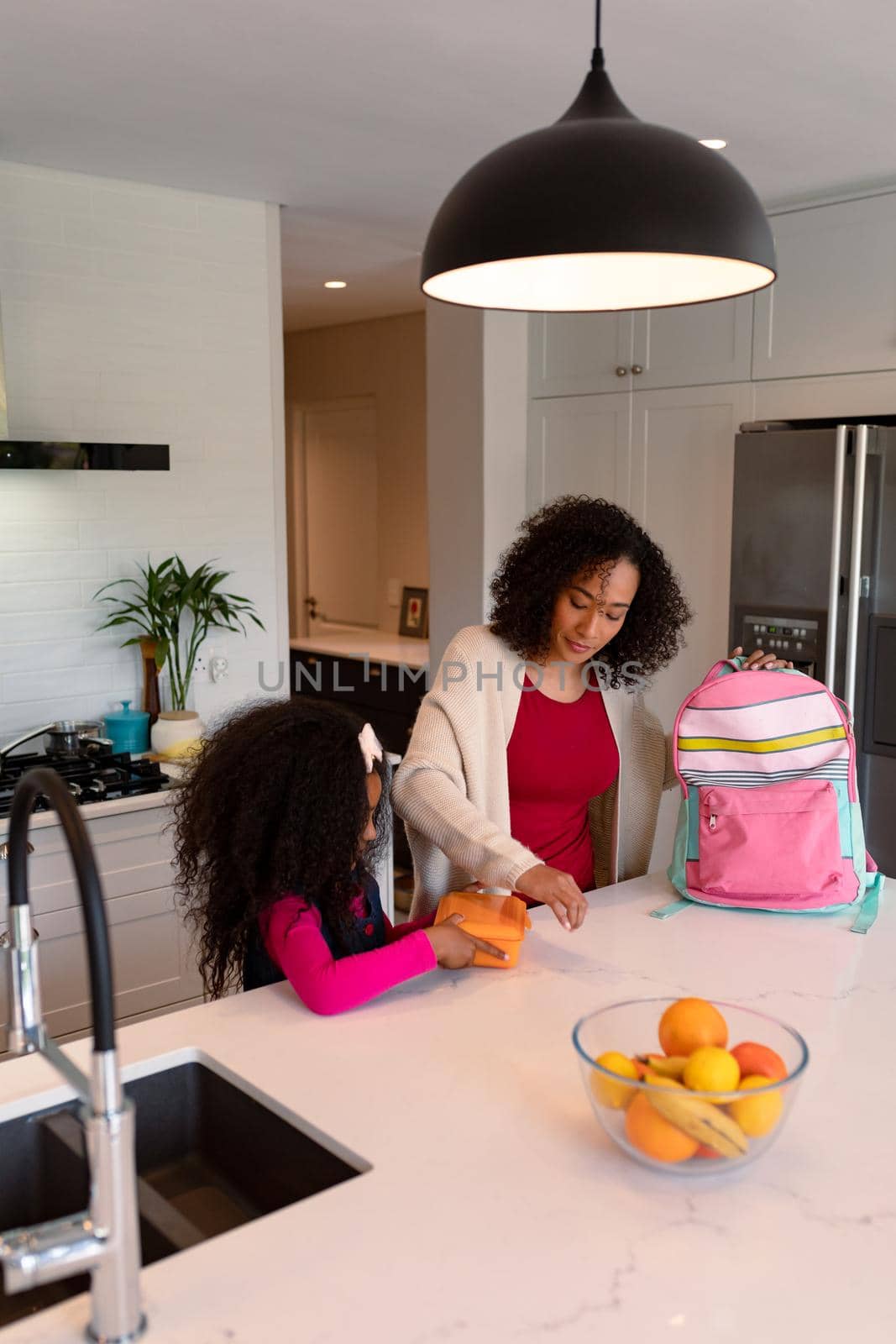 Happy african american mother and daughter preparing lunchbox for school by Wavebreakmedia