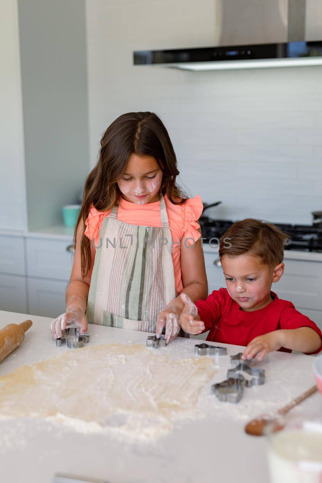 Happy caucasian siblings baking together, making cookies in kitchen. family time, having fun together at home.