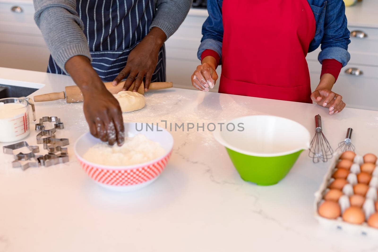 Midsection of african american couple wearing aprons, baking together. family time, having fun together at home.