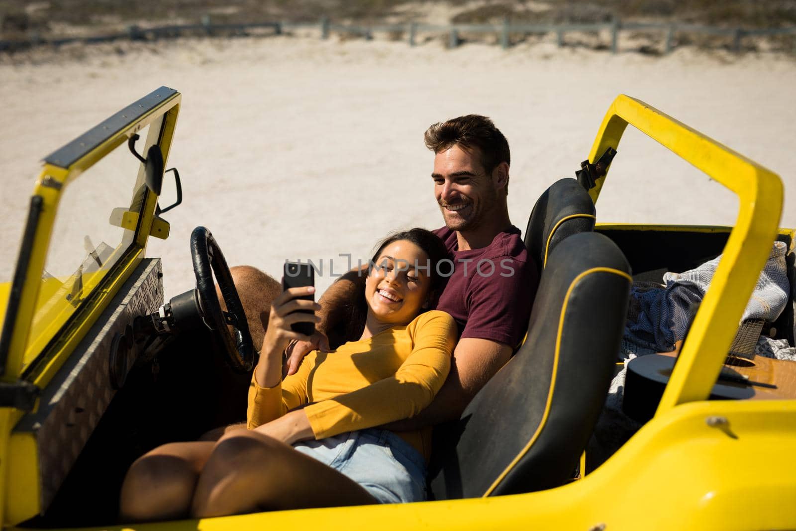 Happy caucasian couple sitting in beach buggy by the sea relaxing. beach break on summer holiday road trip.