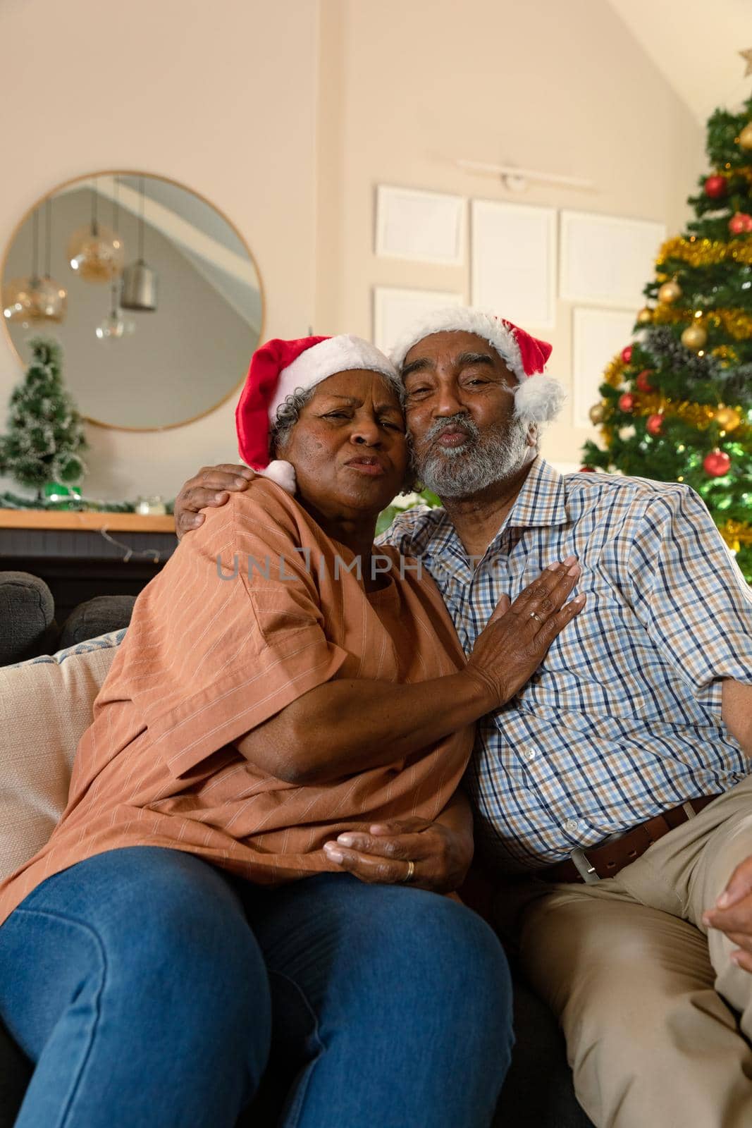 Happy african american couple wearing santa hats having video call at christmas time by Wavebreakmedia