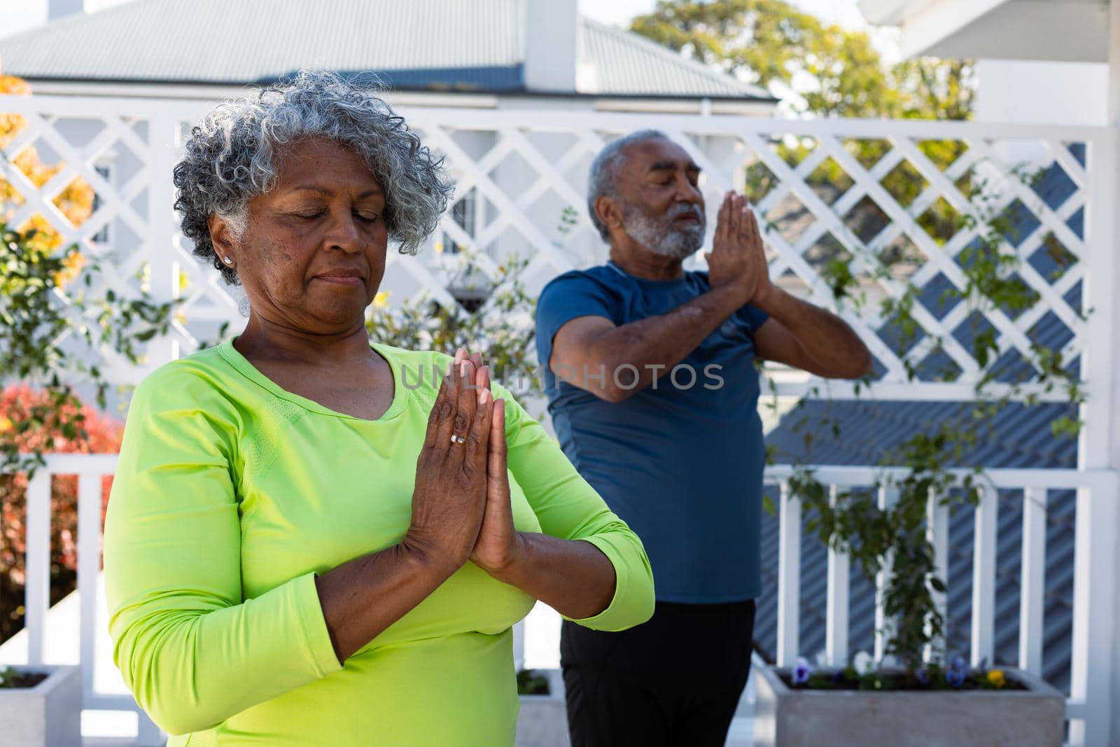 Focused african american senior couple practicing yoga in garden. active and healthy retirement lifestyle at home.