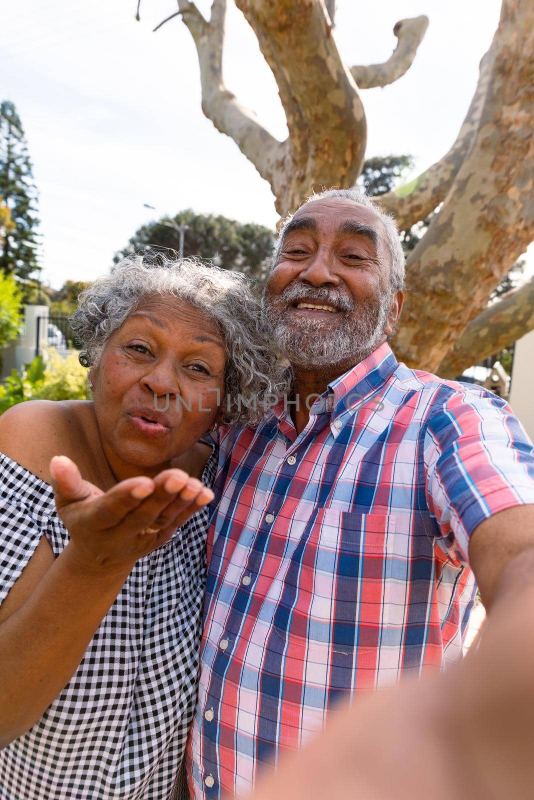 Happy african american senior couple taking selfie and sending kisses. active retirement lifestyle at home and garden.