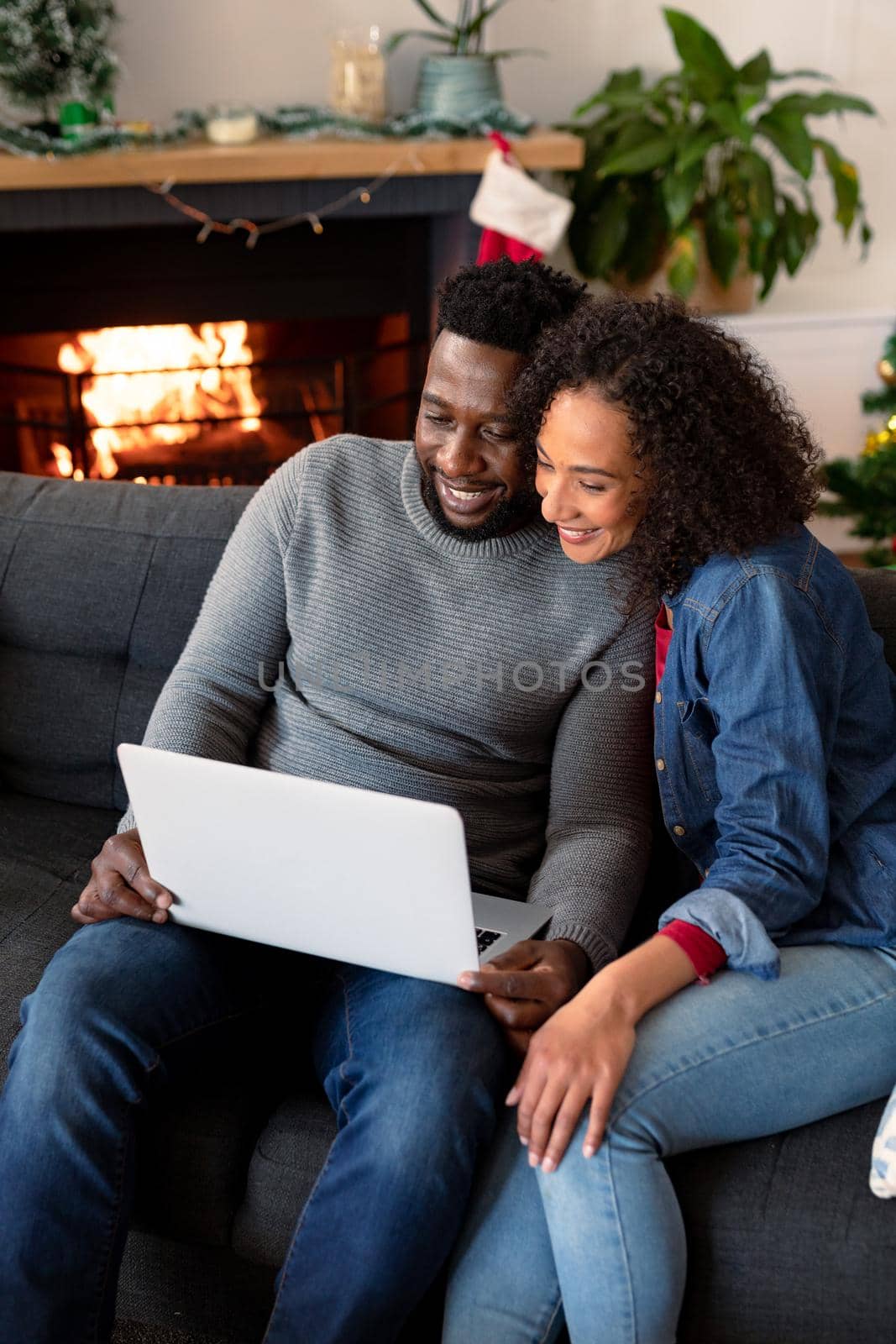 Happy african american couple having video call on laptop, christmas decorations in background. christmas, festivity and communication technology.