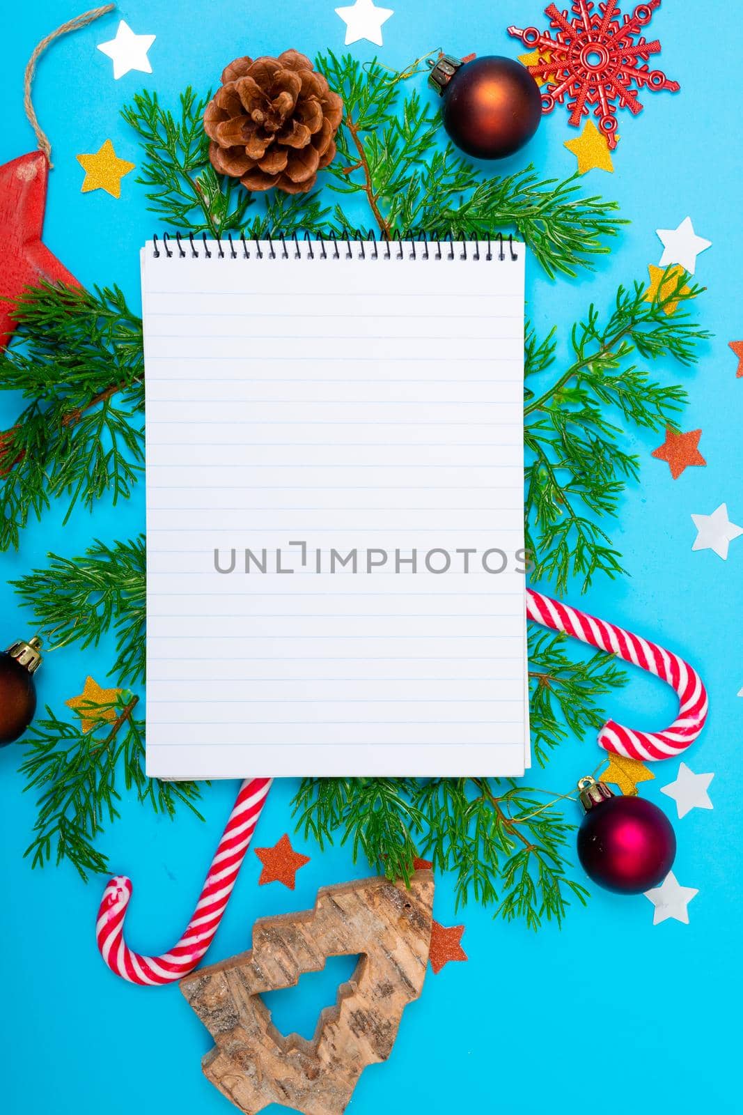Composition of notebook with copy space and christmas decorations on blue background by Wavebreakmedia