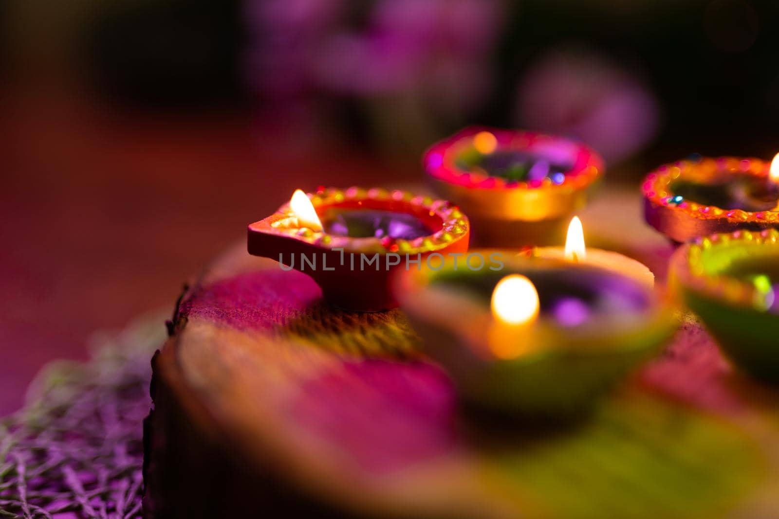 Four lit candles in small decorative clay pots and tea light candle burning on round wooden board. celebration, religion, tradition and ceremony concept.
