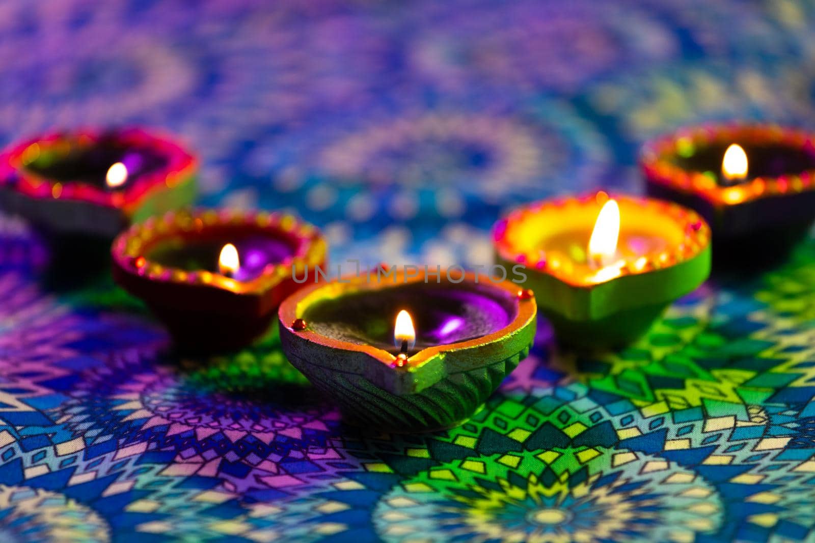 Lit candles in small decorative clay pots burning on patterned table cloth. celebration, religion, tradition and ceremony concept.