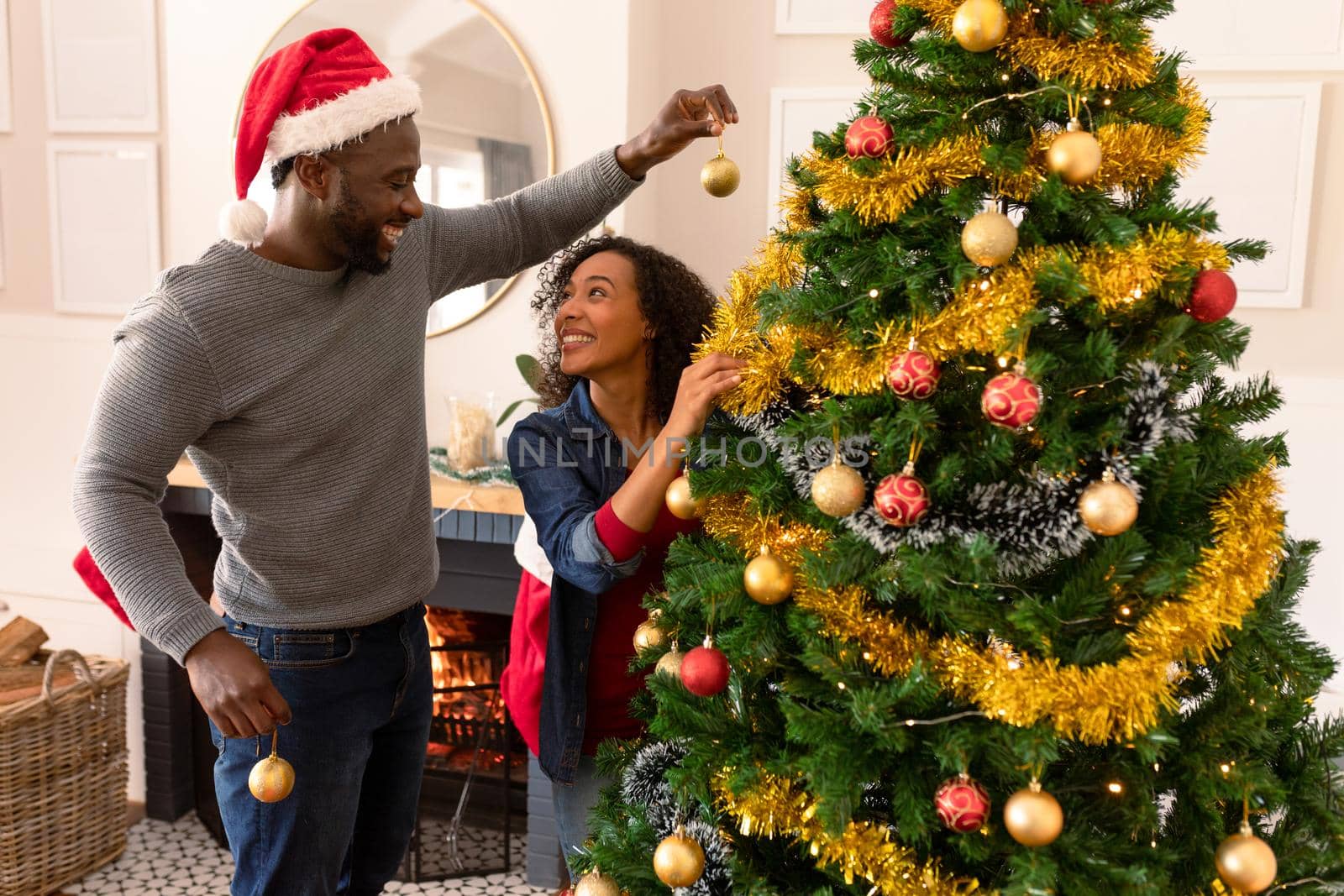 Happy african american couple decorating christmas tree. family christmas time and festivity together at home.