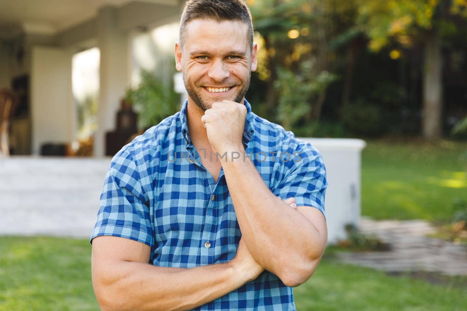 Portrait of smiling caucasian man outside house looking at camera in garden. spending time at home.