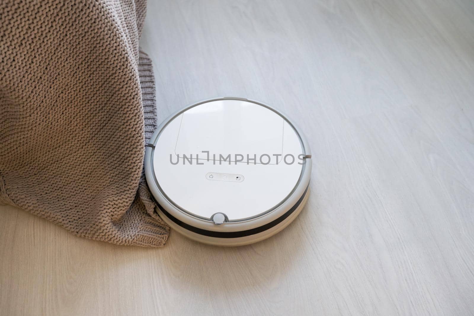 Modern robotic vacuum cleaner on floor in living room. Space for text.