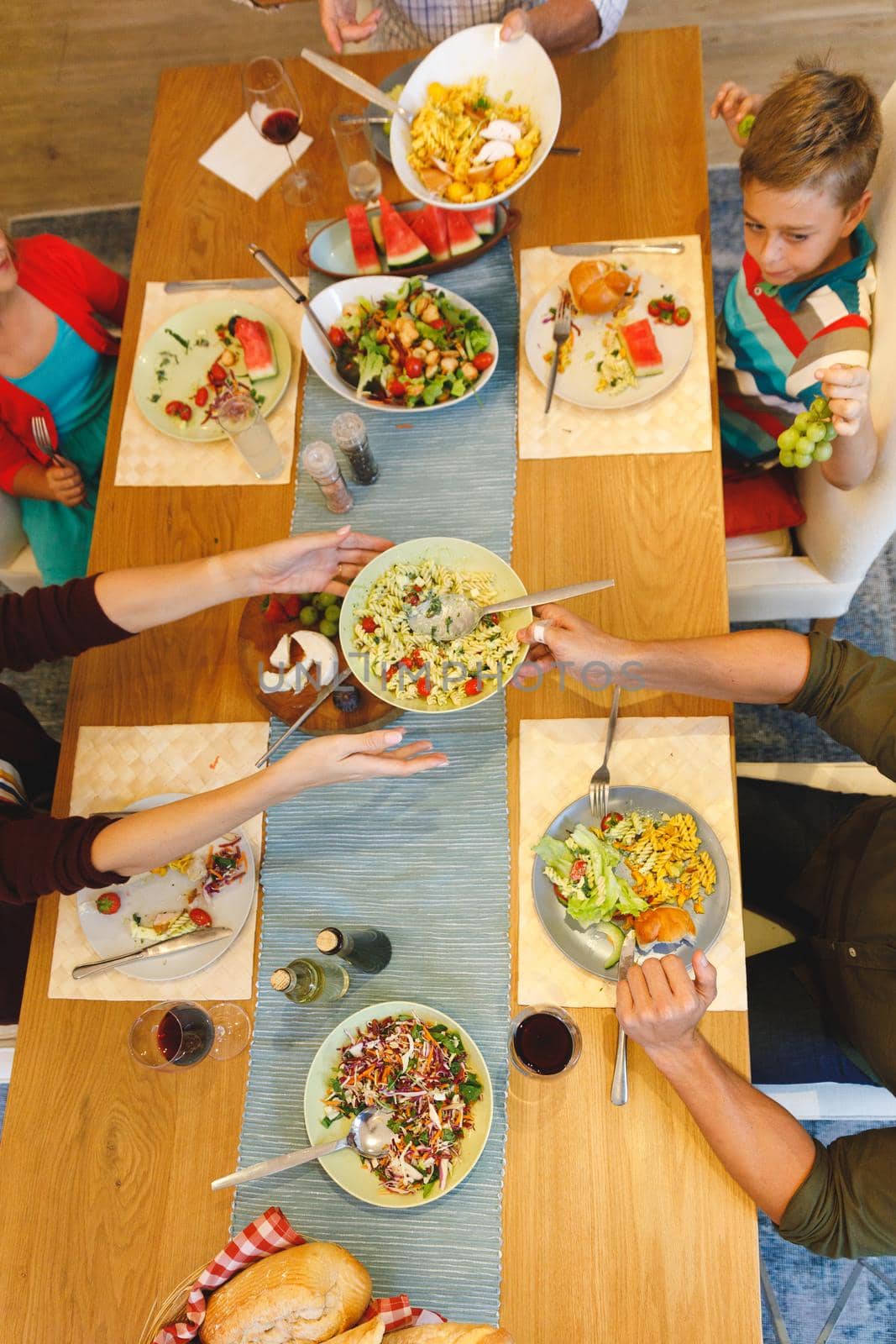 Overhead view of caucasian parents with son and daughter sitting at table and having dinner. family spending time together at home.
