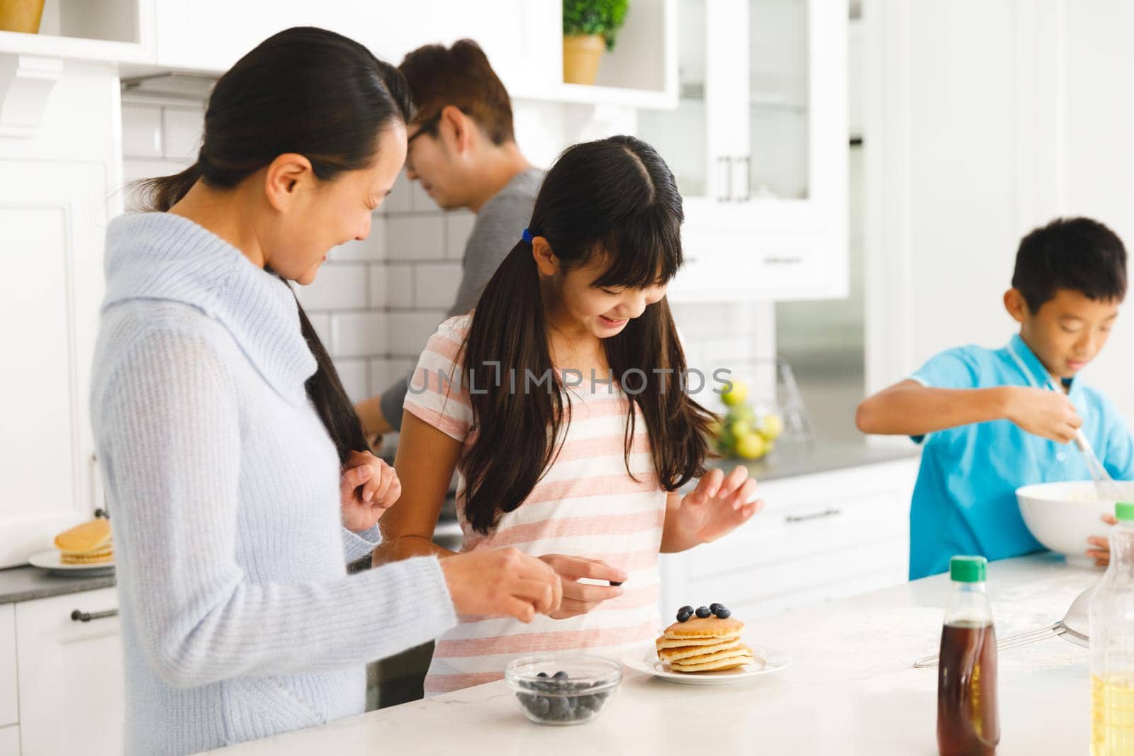 Happy asian parents with son and daughter preparing breakfast in kitchen by Wavebreakmedia