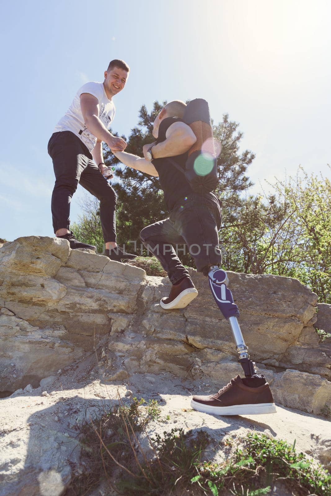 a man on a prosthetic leg travels the mountains. Dressed in black jeans and a T-shirt, he carrying mat.