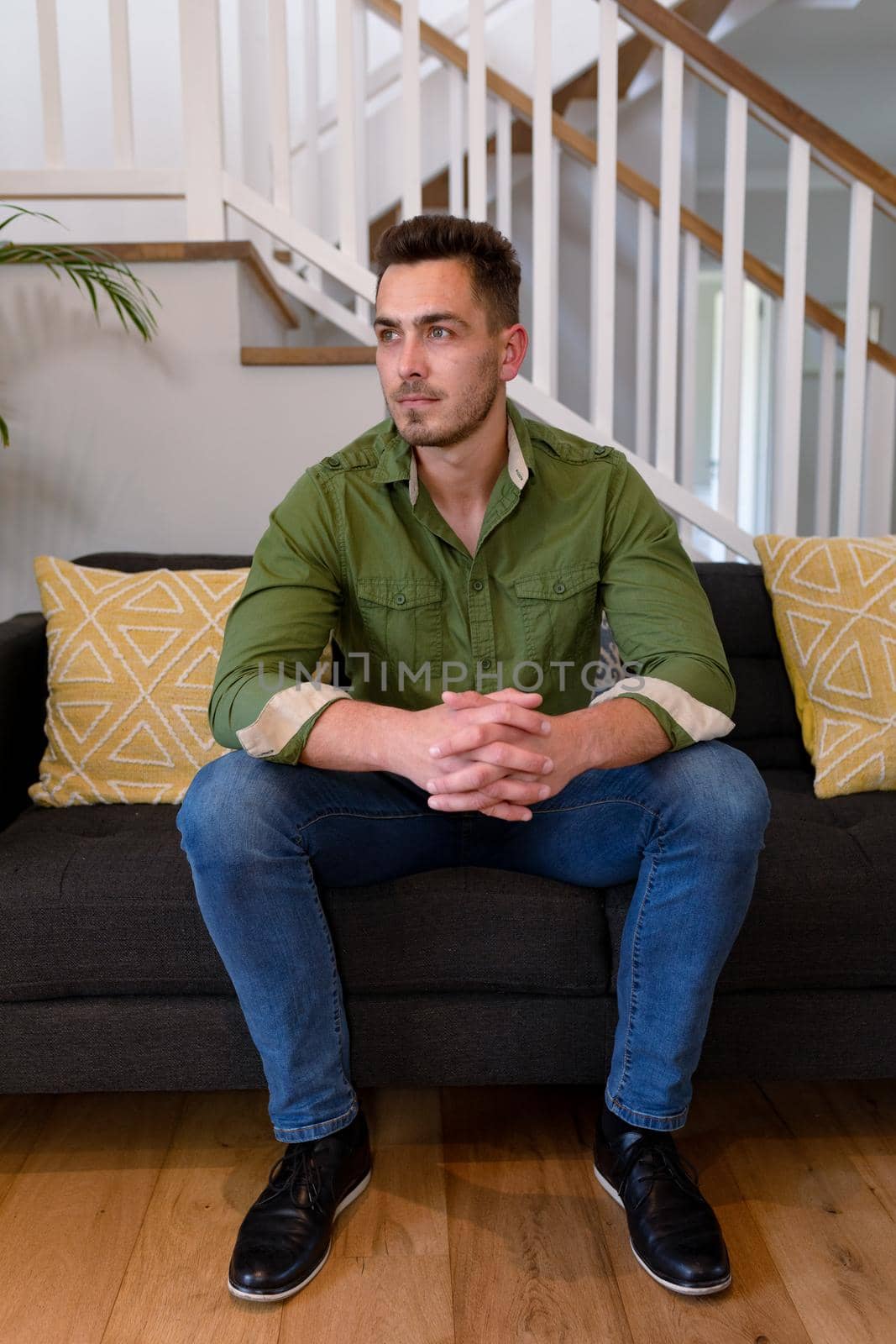 Thoughtful caucasian man sitting on sofa and looking at camera. lifestyle, leisure and spending free time at home.