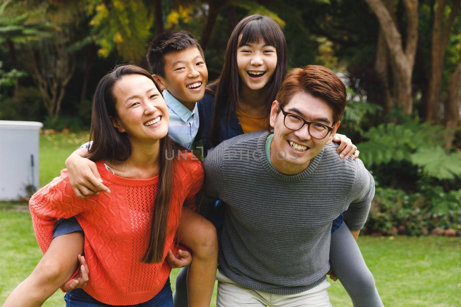 Portrait of happy asian parents, son and daughter smiling outdoors in garden. family enjoying leisure time together at home.