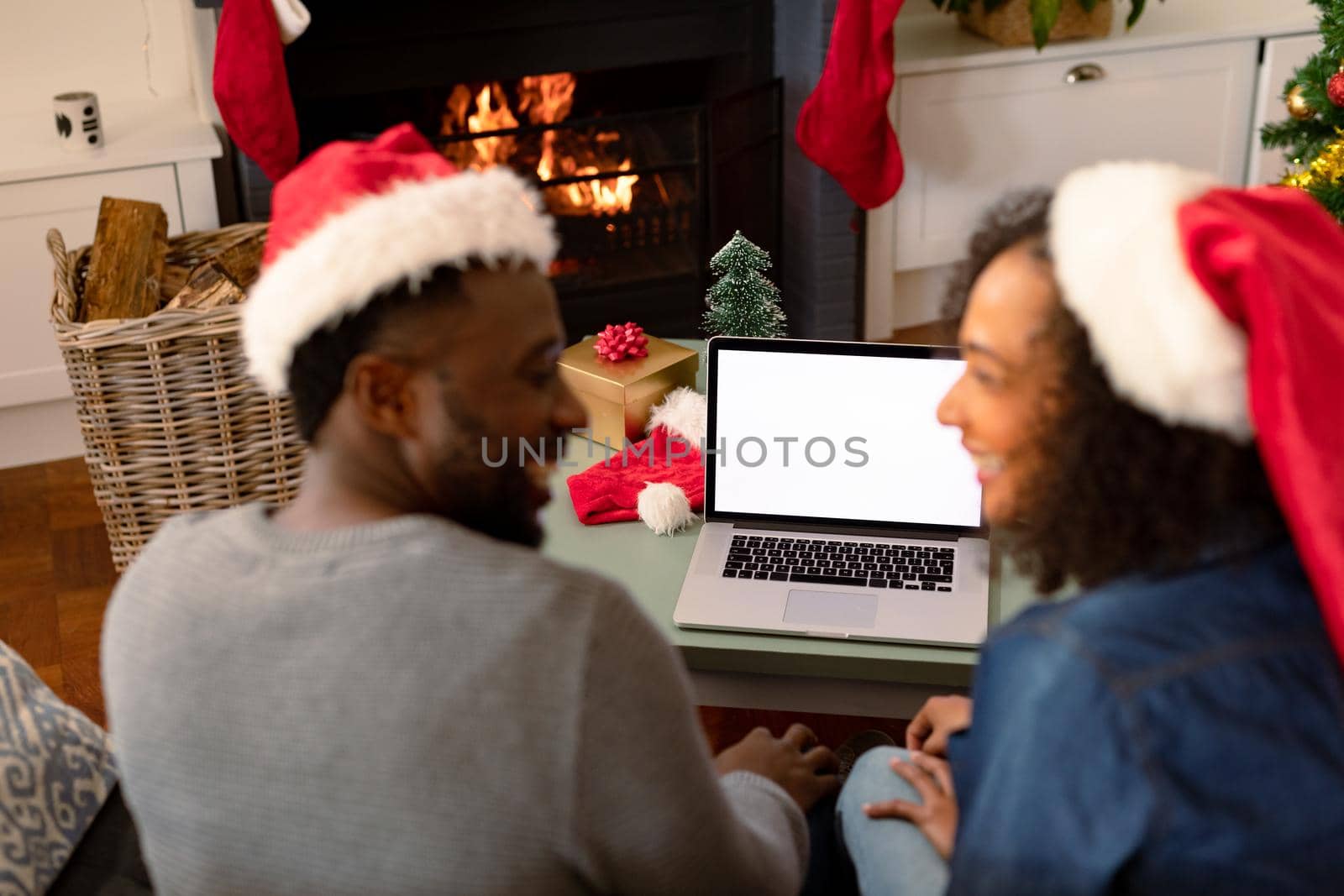 Happy african american couple wearing santa hats, using laptop with copy space on screen by Wavebreakmedia