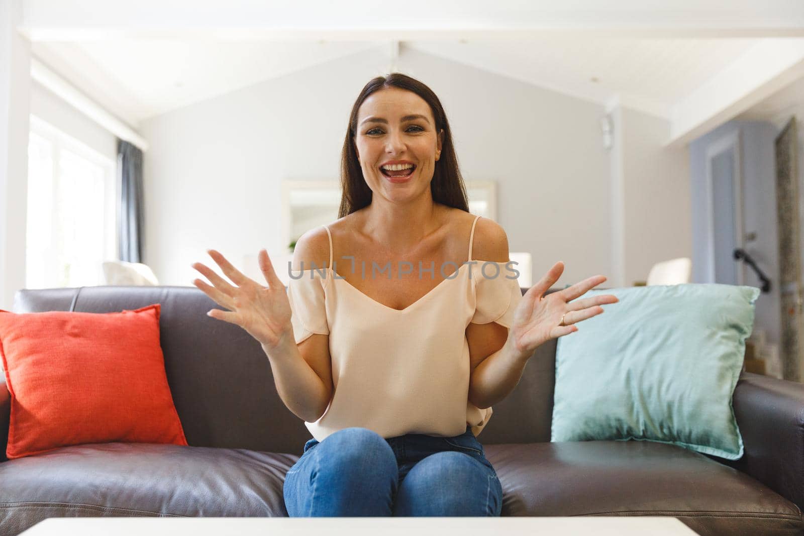 Happy caucasian woman sitting on couch having video call in living room, talking and gesturing. keeping in touch, leisure time at home with communication technology.