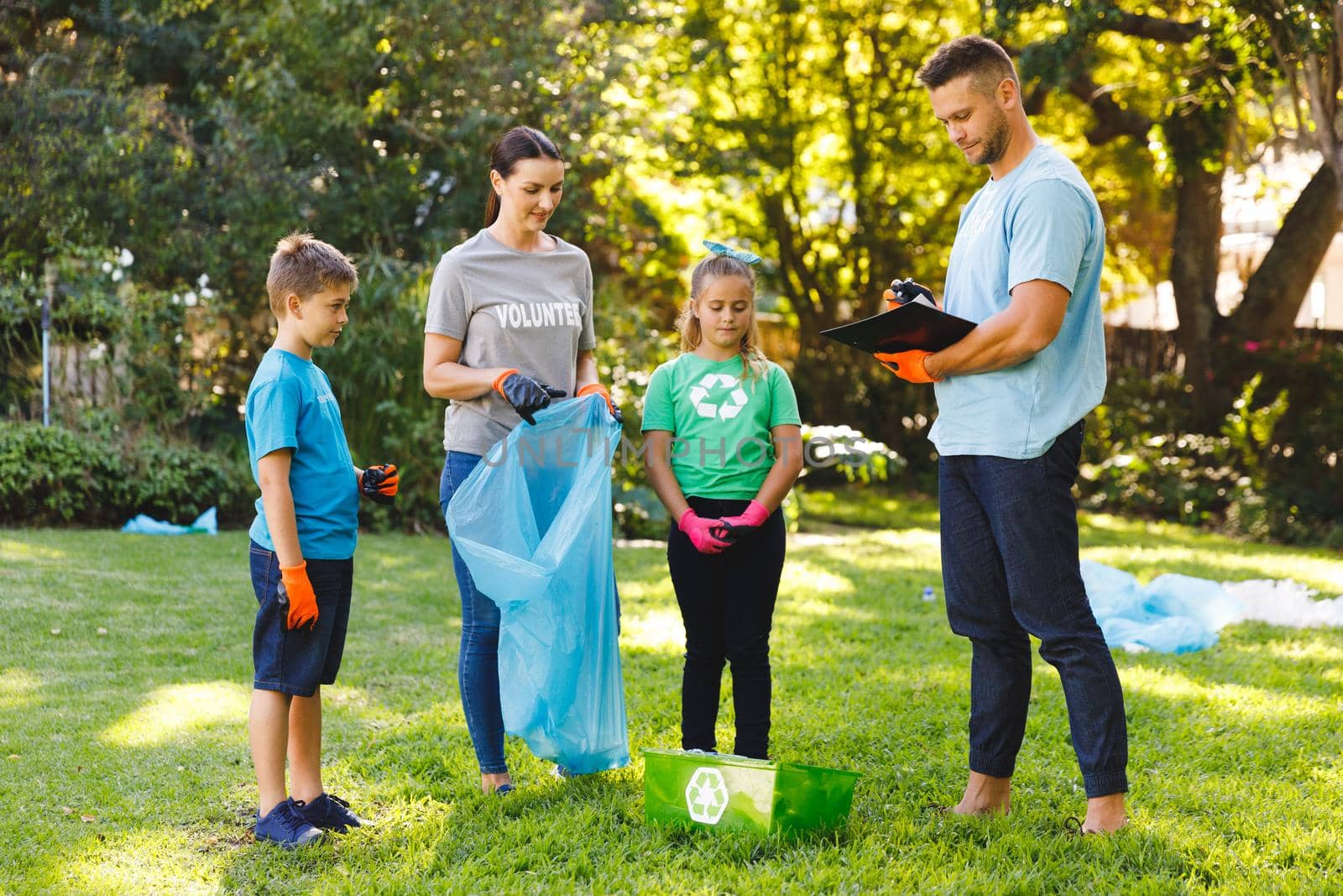 Caucasian parents, son and daughter putting rubbish in refuse sacks in the countryside by Wavebreakmedia