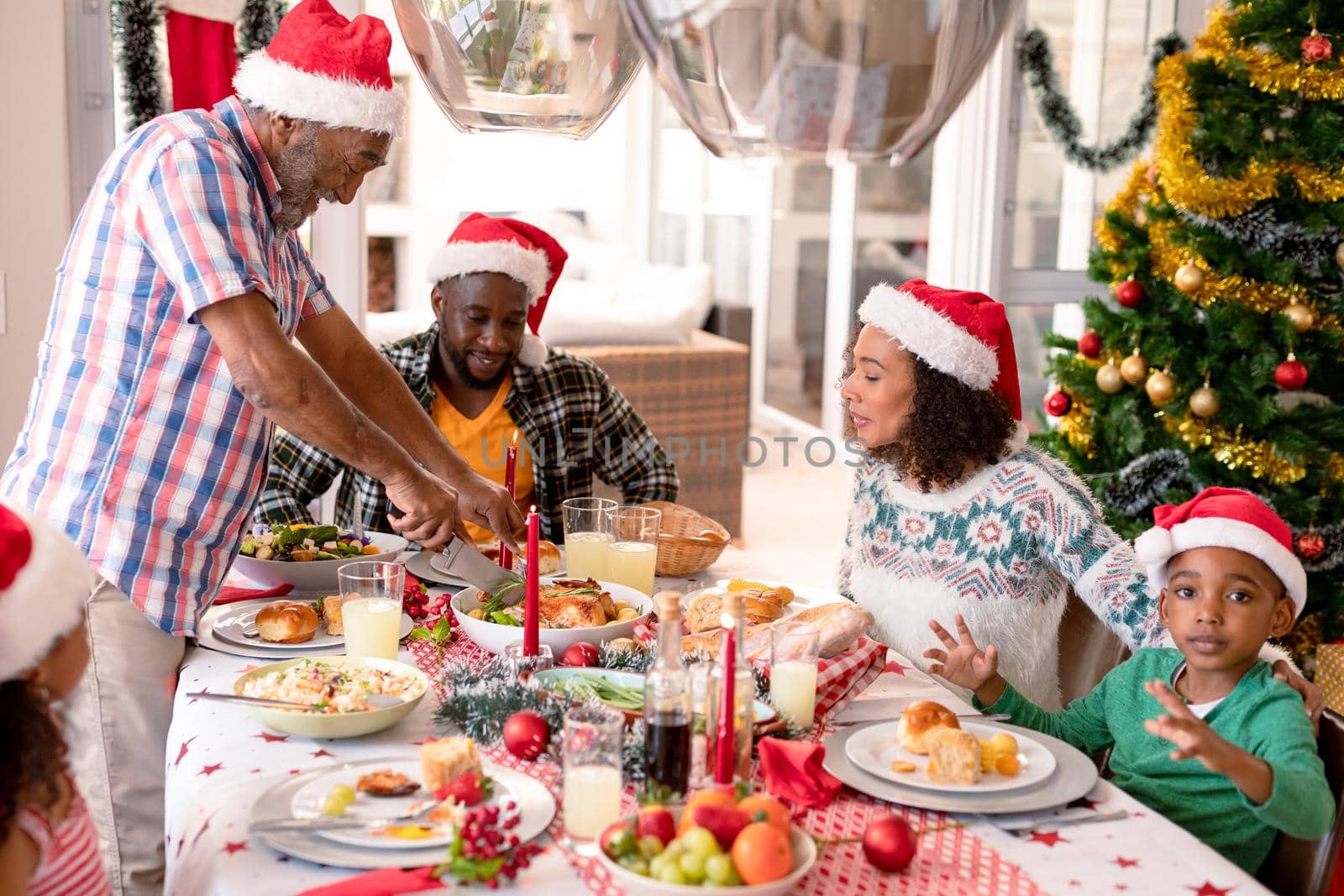 Happy multi generation family wearing santa hats, having christmas meal. family christmas time and festivity together at home.