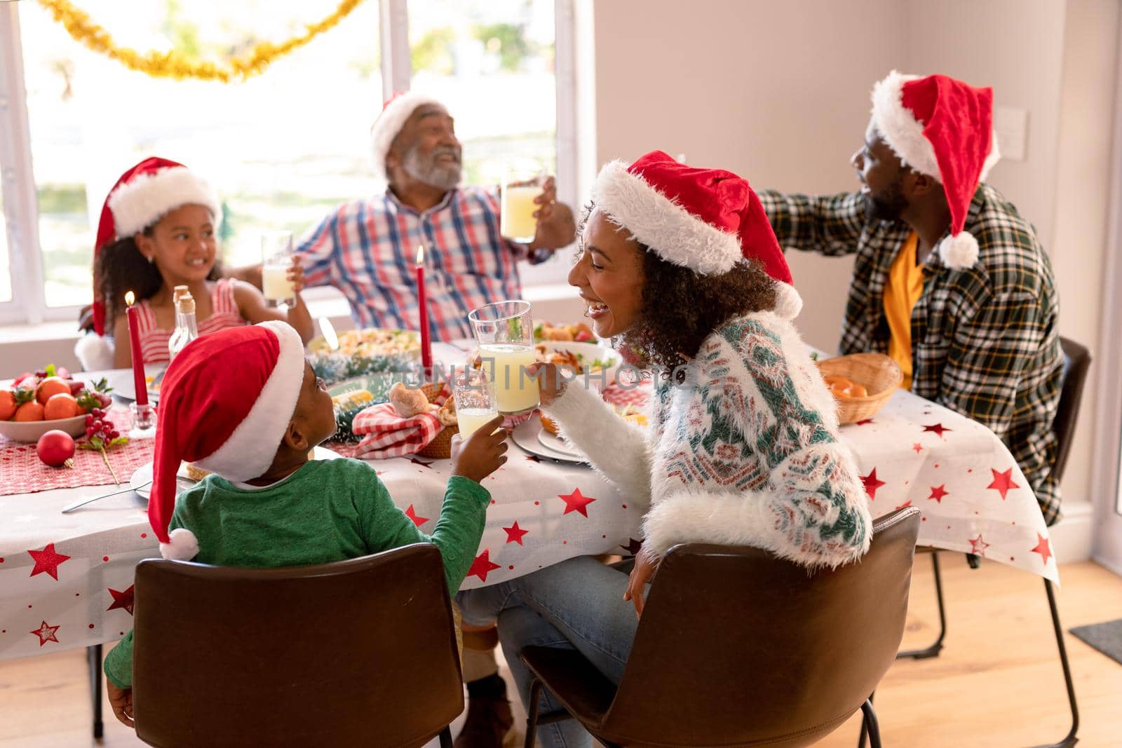 Happy multi generation family wearing santa hats, having christmas meal. family christmas time and festivity together at home.