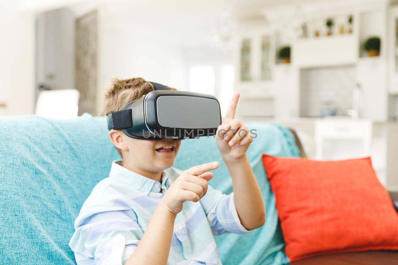 Caucasian boy sitting on couch and using vr headset in living room by Wavebreakmedia