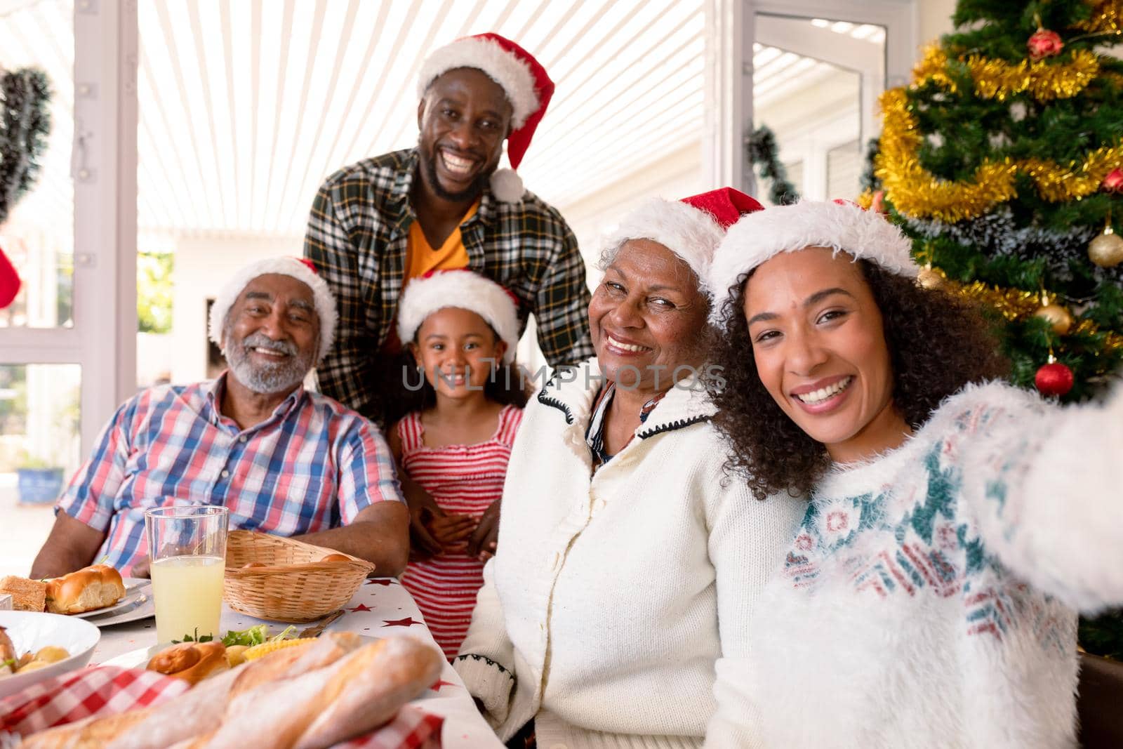 Happy multi generation family wearing santa hats, taking selfie. family christmas time and festivity together at home.