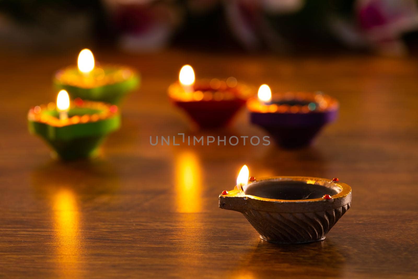 Four lit candles in small decorative clay pots burning on wooden table top. celebration, religion, tradition and ceremony concept.