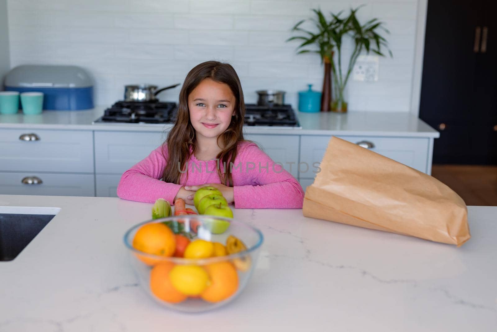 Happy caucasian girl unpacking groceries in kitchen by Wavebreakmedia