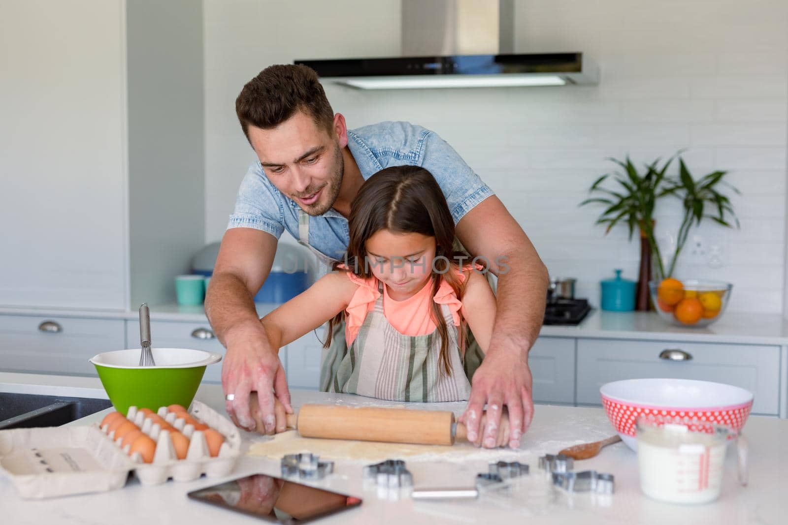 Happy caucasian father and daughter baking together, making cookies in kitchen. family time, having fun together at home.