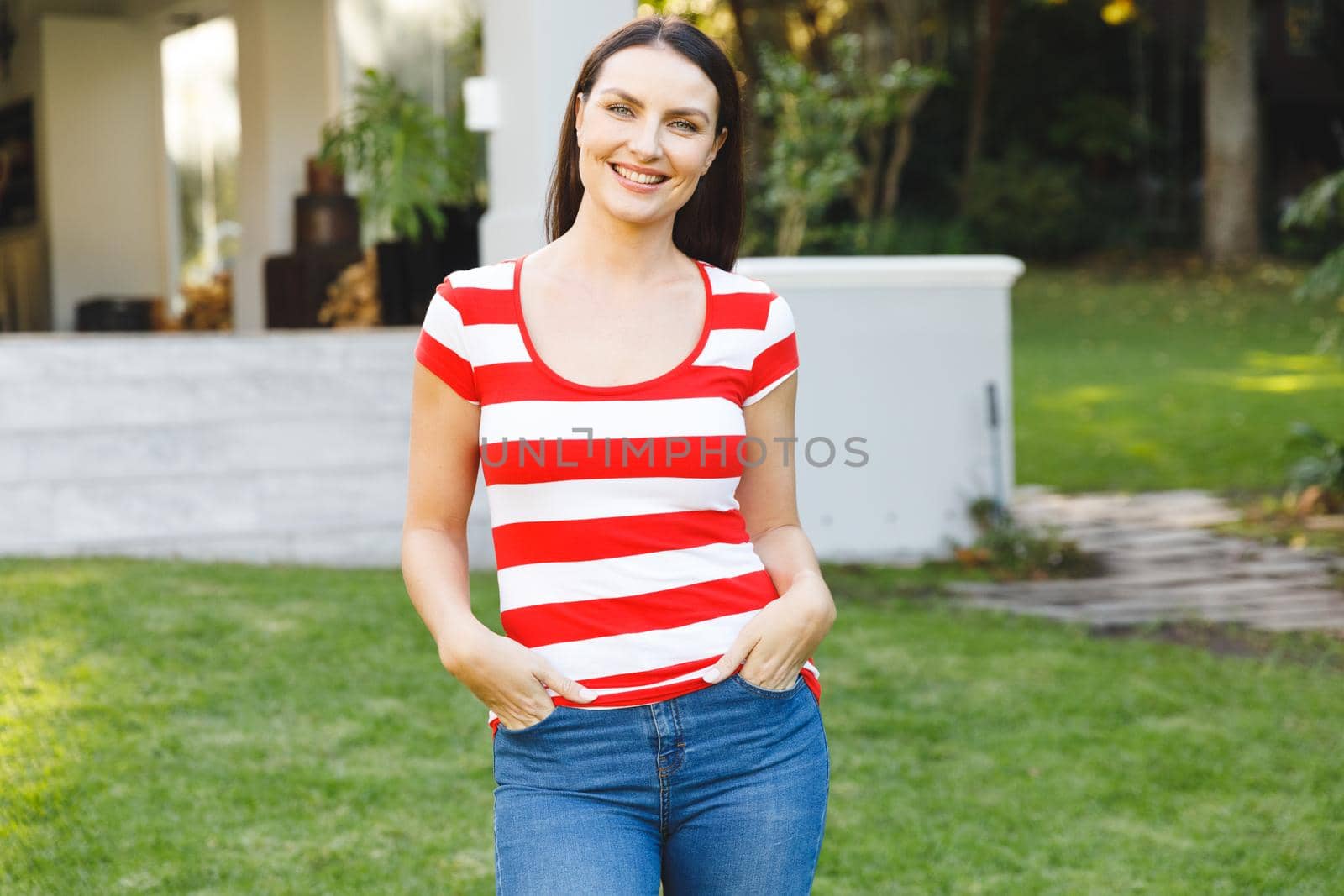 Portrait of smiling caucasian woman outside house looking at camera in garden. spending time at home.