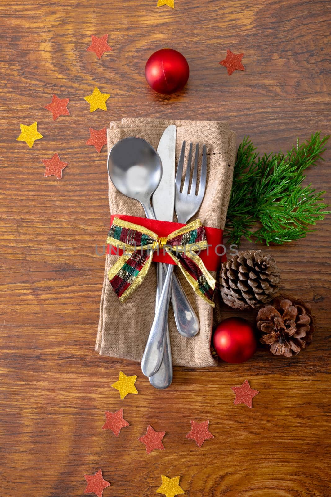 Composition of christmas decorations with cutlery and napkin on wooden background. christmas, tradition and celebration concept.