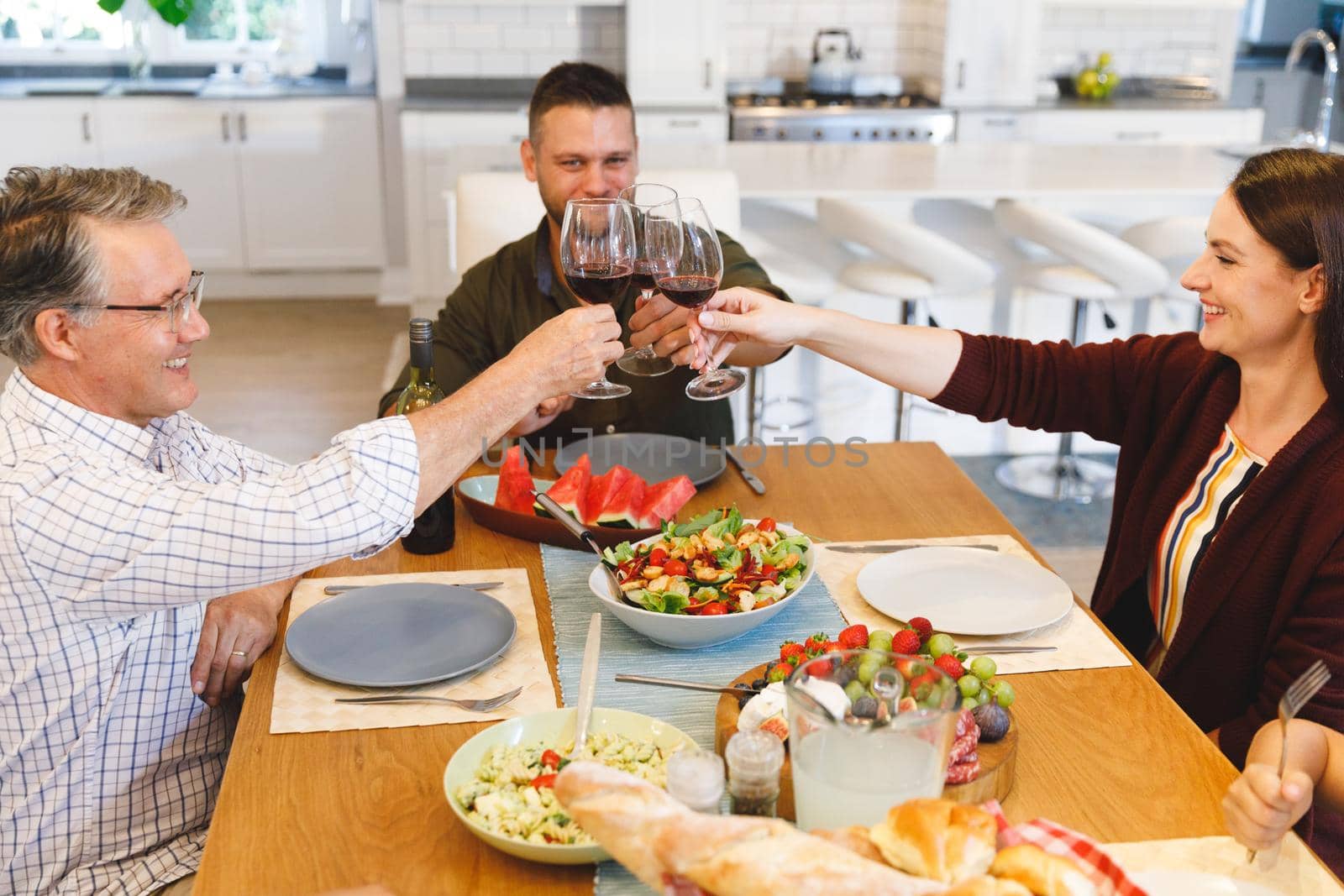 Caucasian grandfather and parents with son and daughter sitting at table and having dinner by Wavebreakmedia