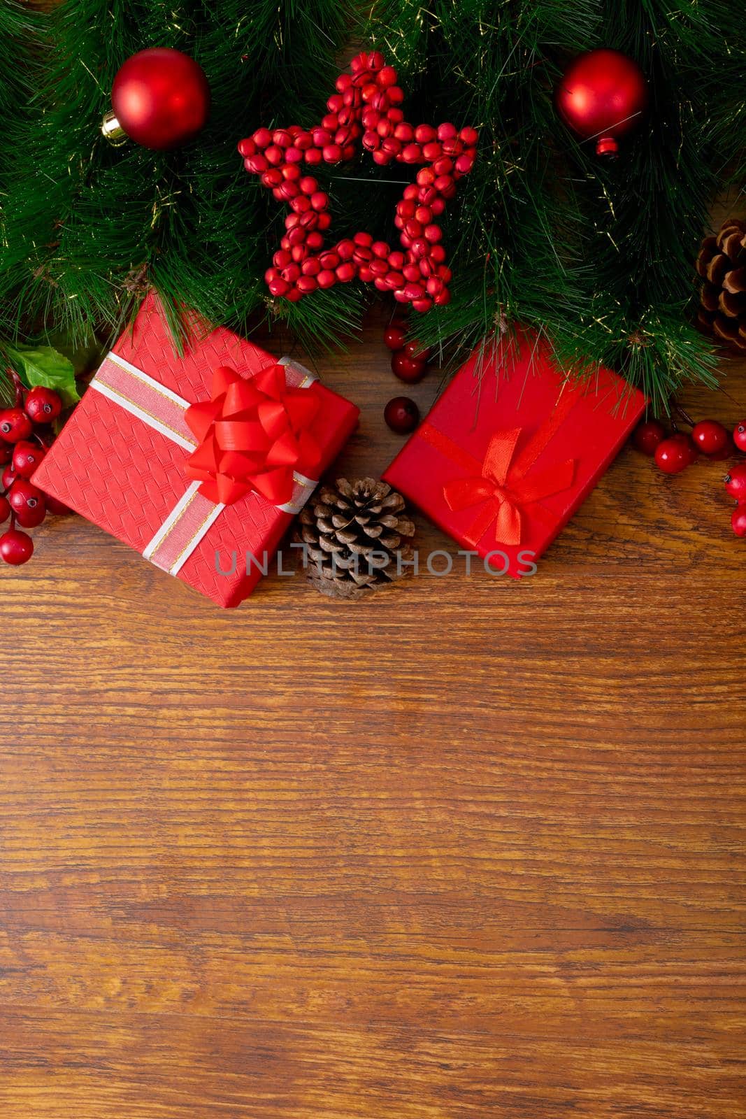 Composition of christmas decorations with baubles, presents and copy space on wooden background by Wavebreakmedia