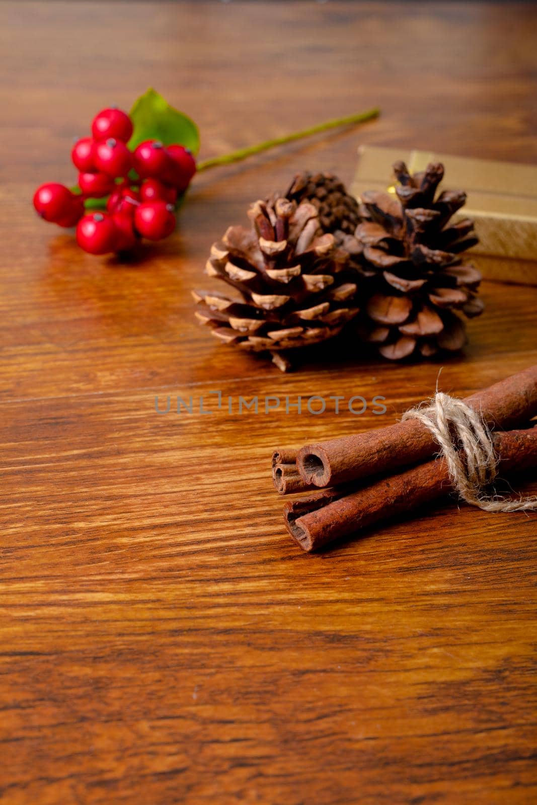 Composition of christmas decorations with pine cones and cinnamon on wooden background by Wavebreakmedia