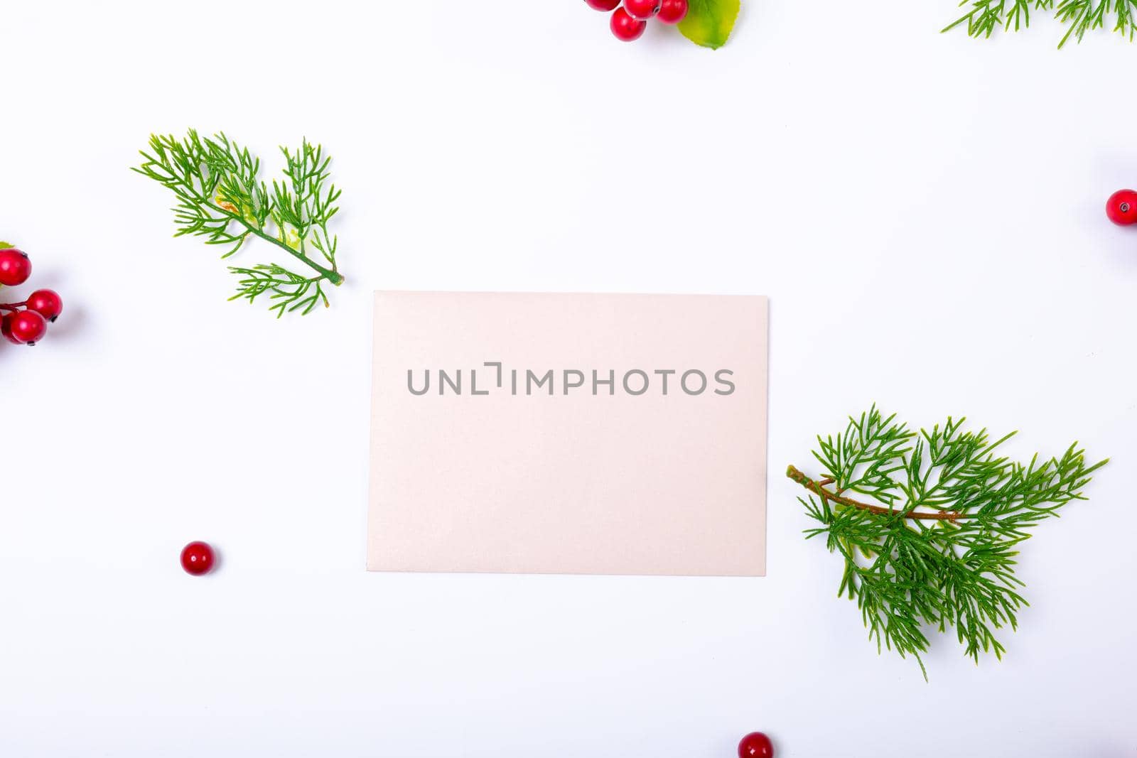 Composition of white card with copy space and branches with berries on white background. christmas, tradition and celebration concept.
